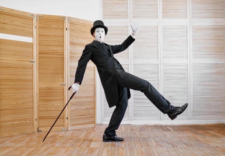 A male mime dressed in black with a cane. 