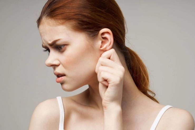 A woman gently tugs her earlobe.