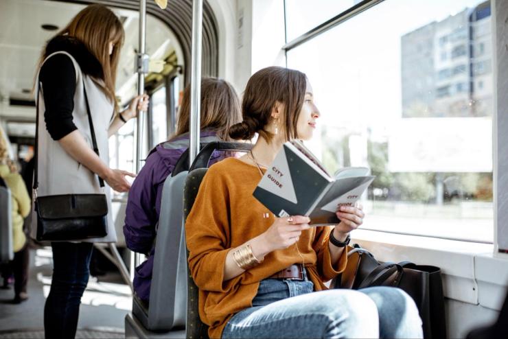A woman passenger using public transportation while reading a book.