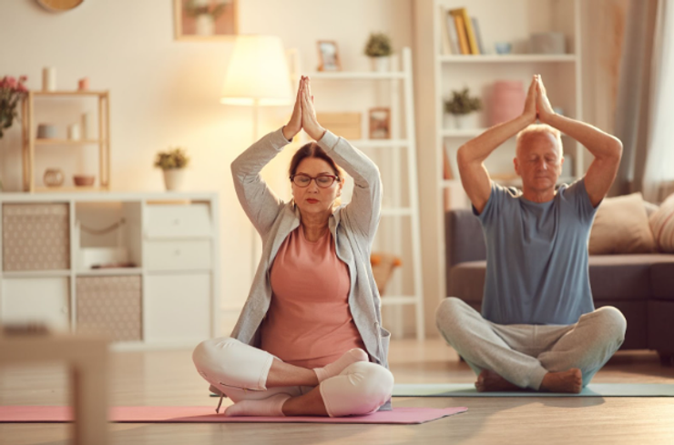 Older man and older woman in sitting yoga pose, with their eyes closed.
