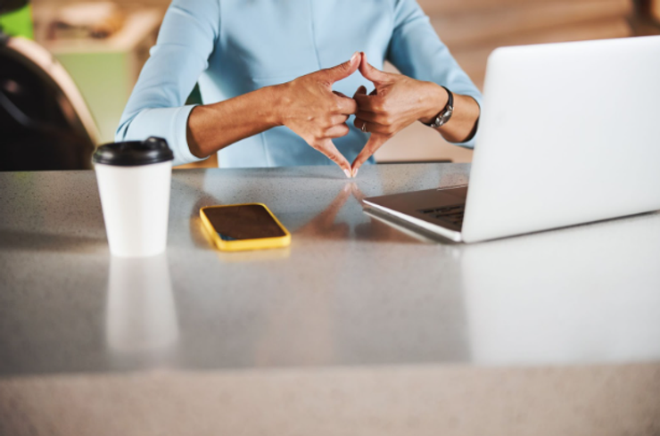 Woman in blue using international sign language on a video call. In ASL, the sign is “award.”