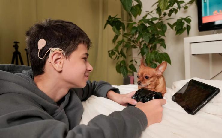 Boy with a cochlear implant playing a video game.