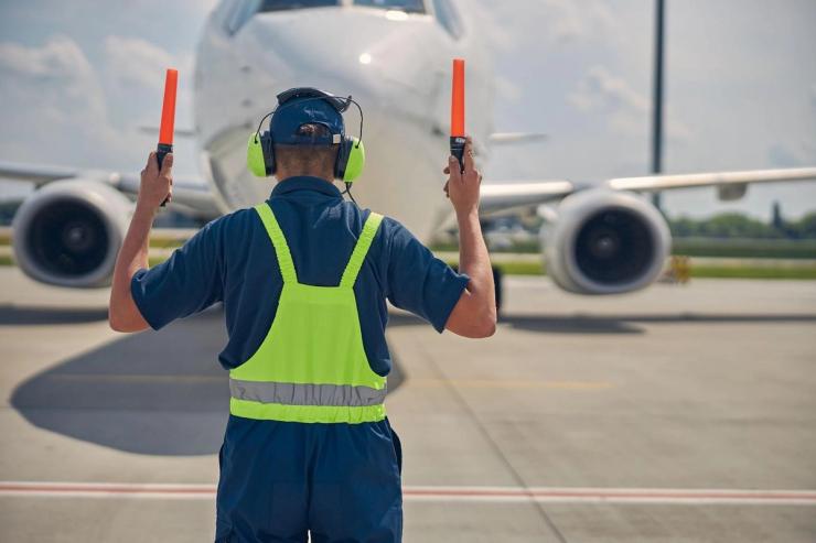 Aviation marshall wearing hearing protection on the tarmac‍