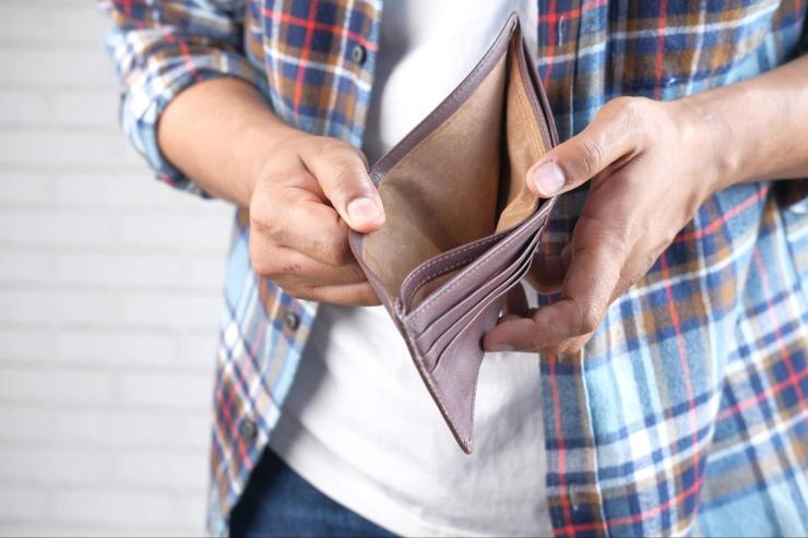 A man in a plaid shirt holding an empty wallet.