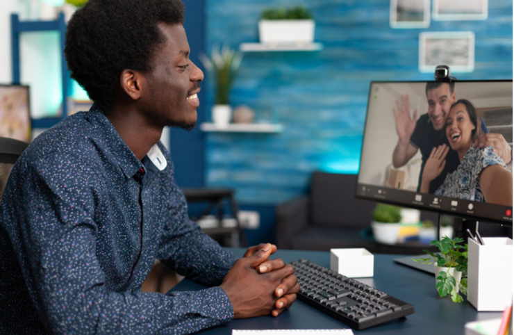 Black person smiling while on a video call with two people.