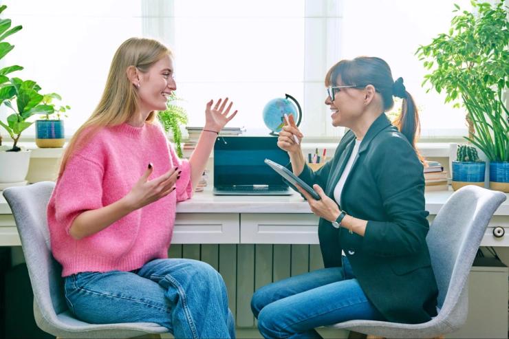A woman with blond hair is sitting and talking to a therapist also sitting.
