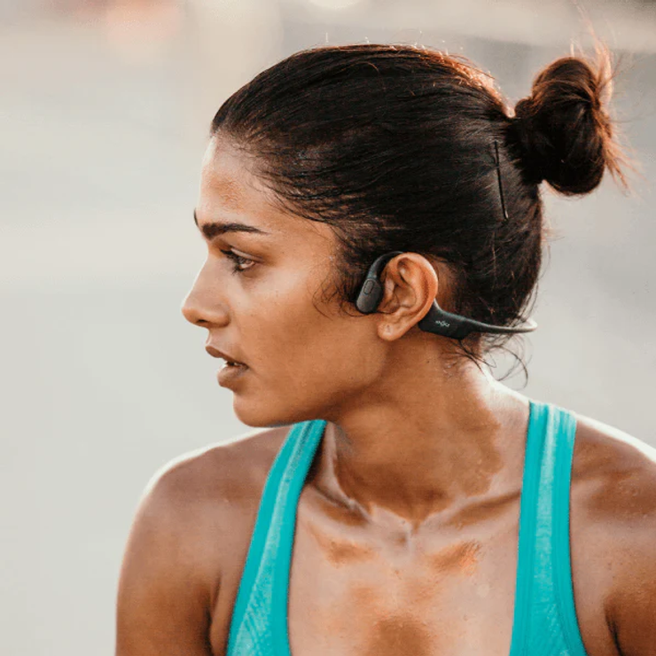 A woman in activewear wearing Shokz bone-conduction headphones