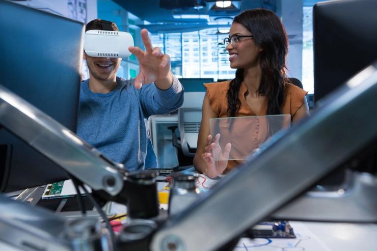 Two people in front of computers using VR technology.