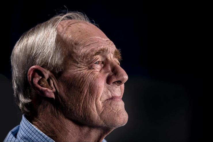 An older man with a hearing aid.