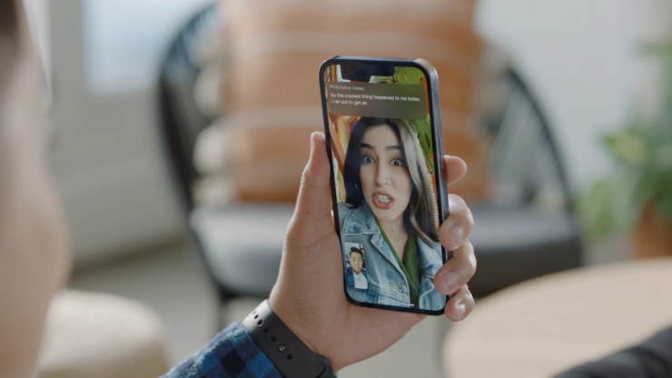 Person holding a smartphone during a video call, showing real time captions and text communication on the screen.