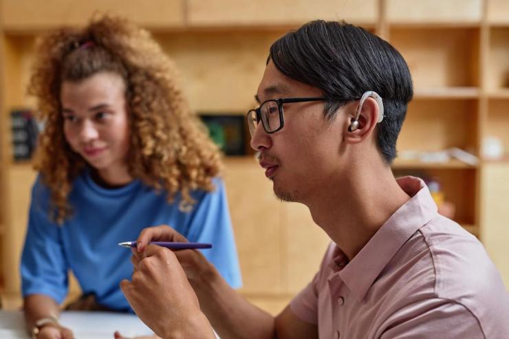 A young Asian male wearing a hearing amplifier.