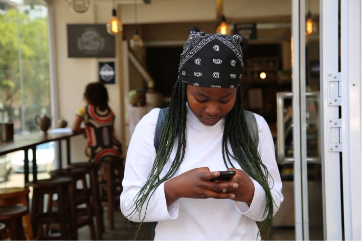 A young woman holding a smartphone and typing a text message.