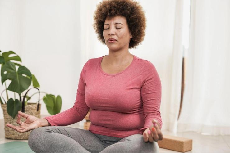 Woman meditating at home as part of natural ways to protect hearing health and reduce stress linked to hearing loss