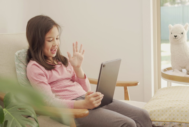 Young girl with long brown hair holding a tablet while on a video call