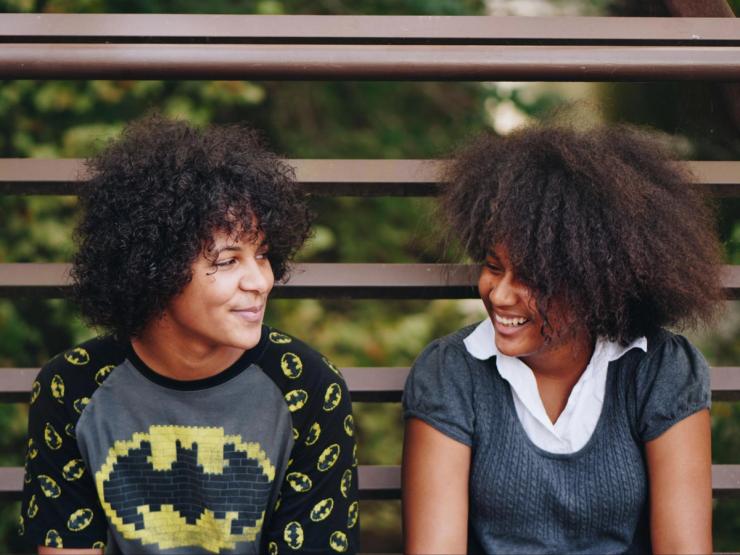 Two women sit side by side with friendly smiles.