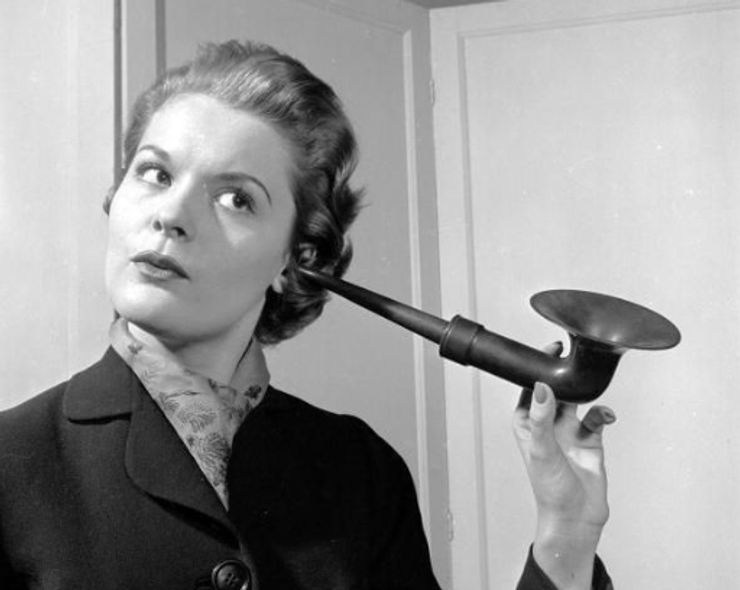 Black and white image of a woman using an ear trumpet.