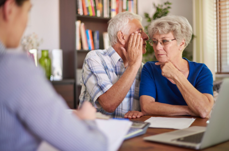 Man whispering to his wife ear in a doctor's office.