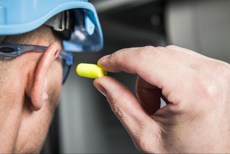 Factory Worker in Blue Hard Hat Preparing To Use Foamy Plug.