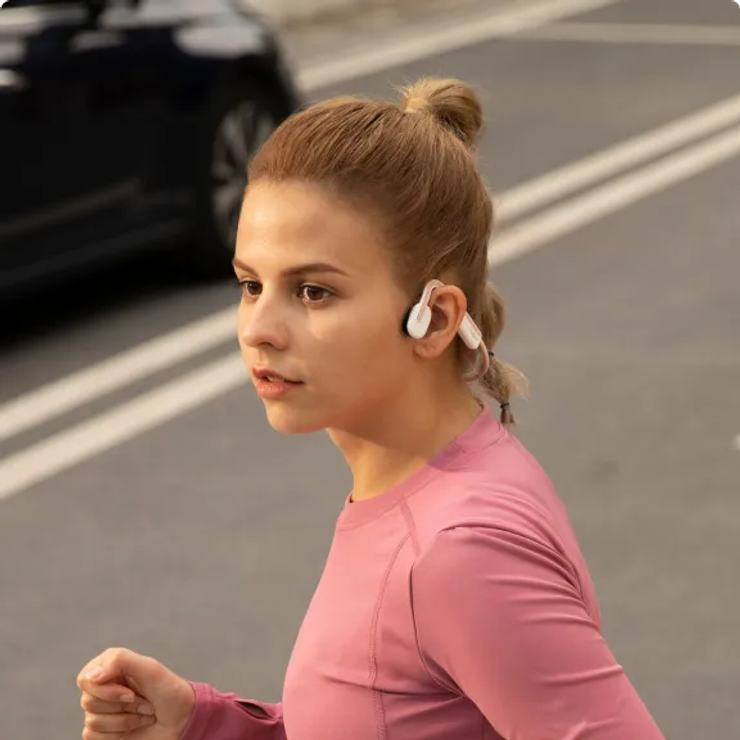 A woman jogging in the street wearing bone-conduction headphones