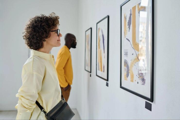 Two people looking at art displays on a wall in a museum.