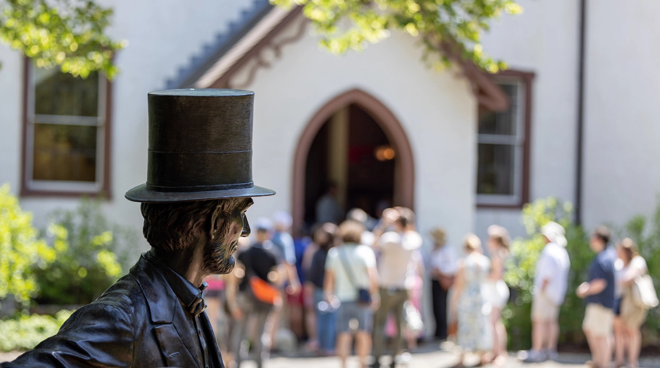 A statue and bust of President Lincoln faces toward a crowd of patrons in front of President Lincoln’s Cottage