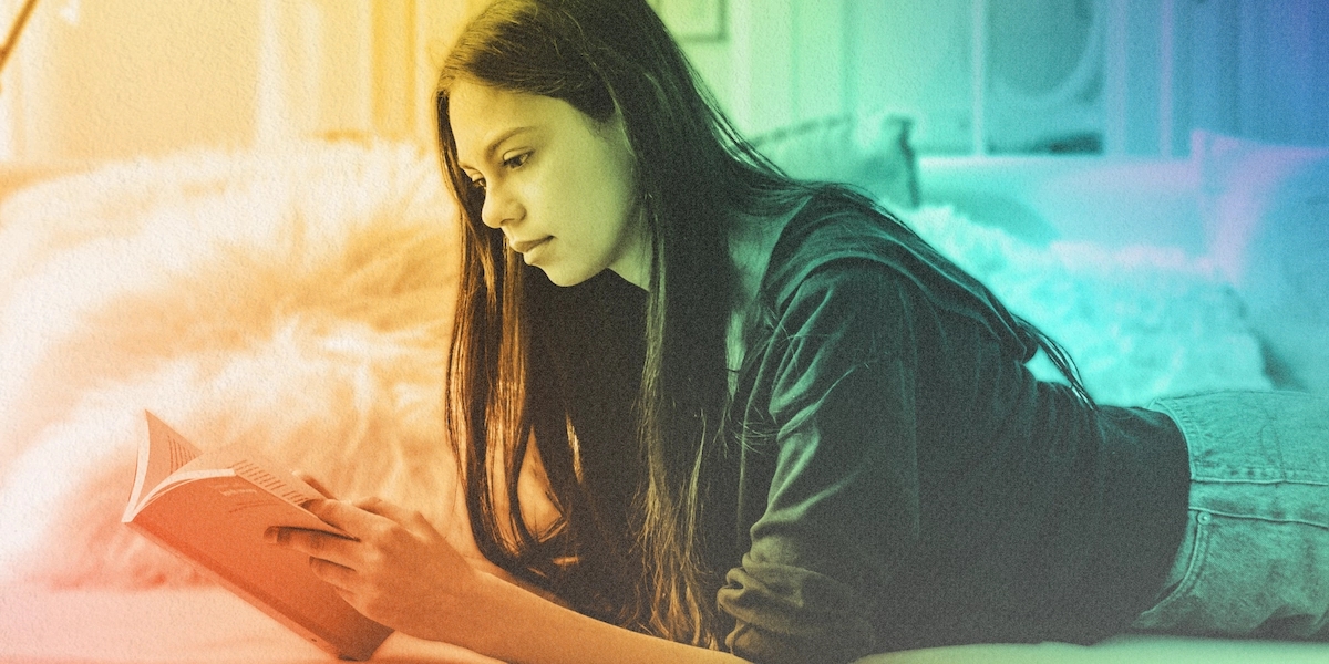 A red, gold, green and blue gradient photo of a young person reading a banned book in their bedroom.