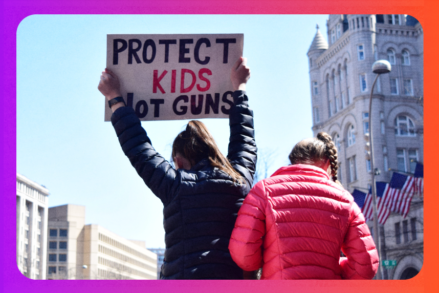 Person holding up a sign that reads "Protect kids, not guns" at a rally