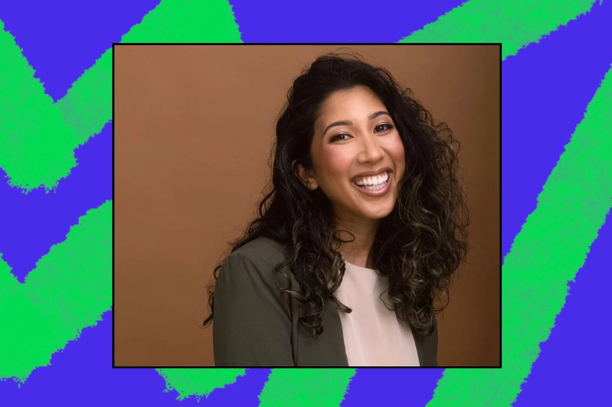 A smiling individual with curly hair, wearing a blazer, stands against a warm brown background framed by a vibrant blue and green abstract design. This image represents community engagement and civic leadership opportunities.