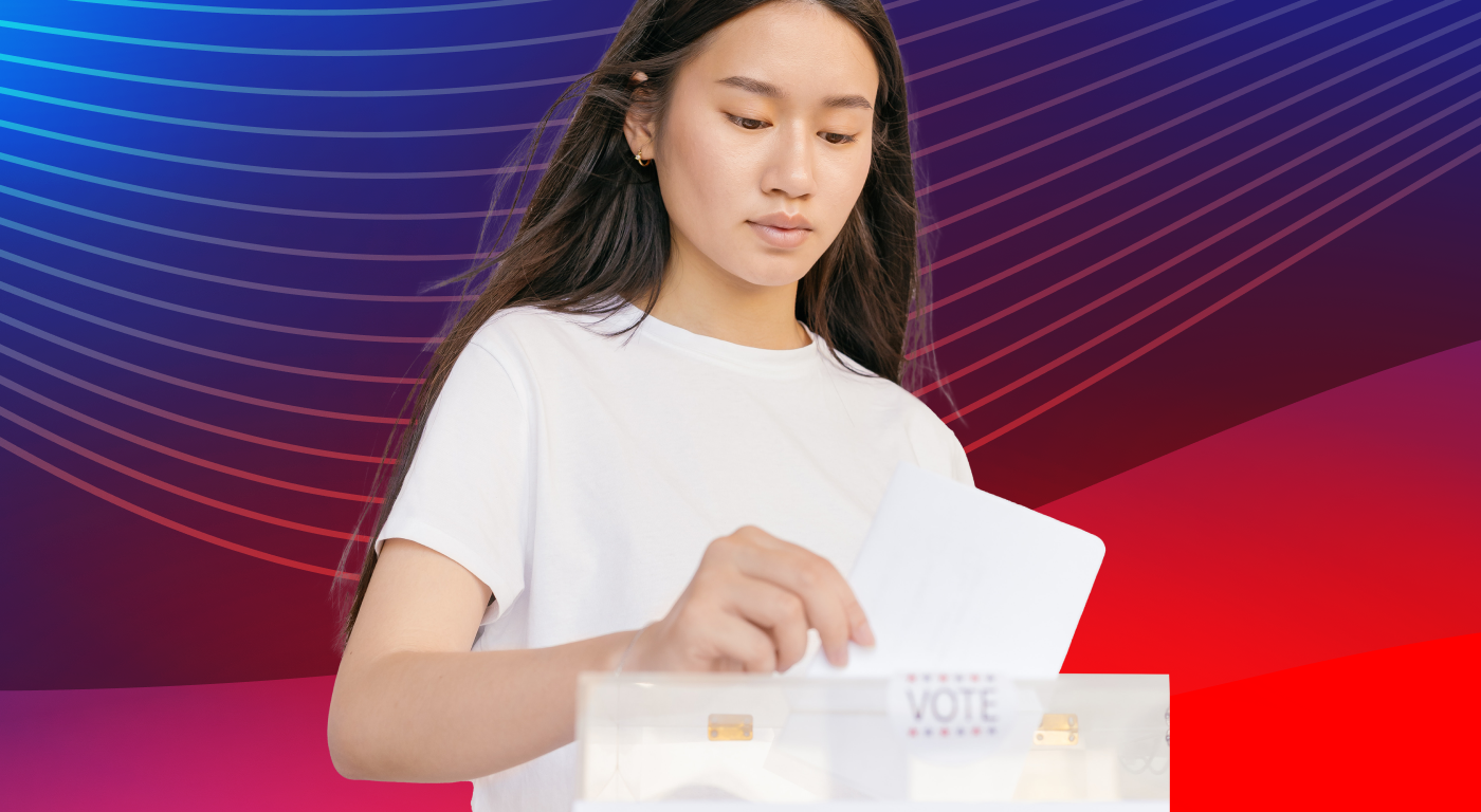 A young person with long straight dark hair, wearing a white t-shirt, dropping a ballot into a voting box