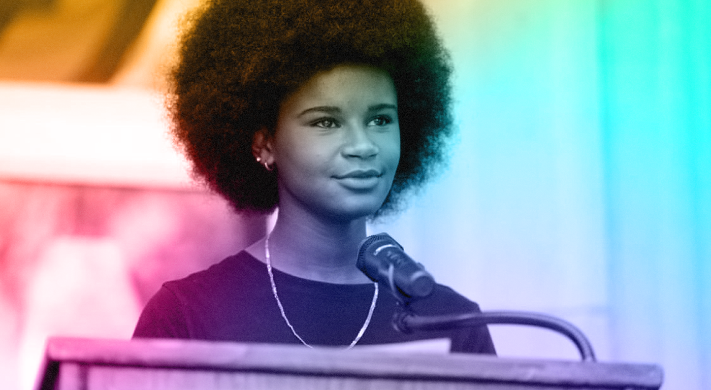 Multi color gradient headshot of Marley Dias speaking at a podium; with fluffy afro natural hair, dark top, and necklace