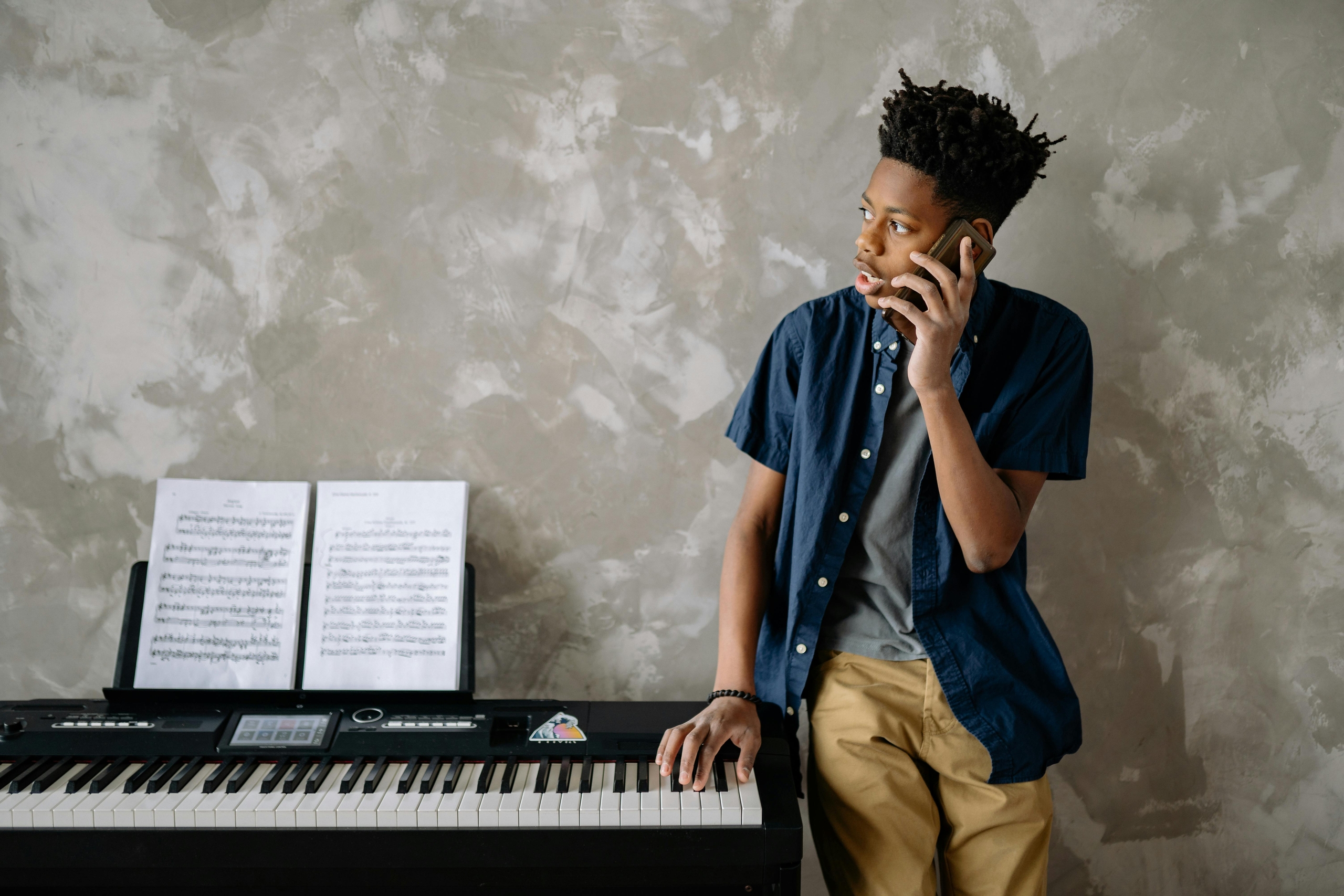 A young person is talking on their mobile phone while leaning on their keyboard.