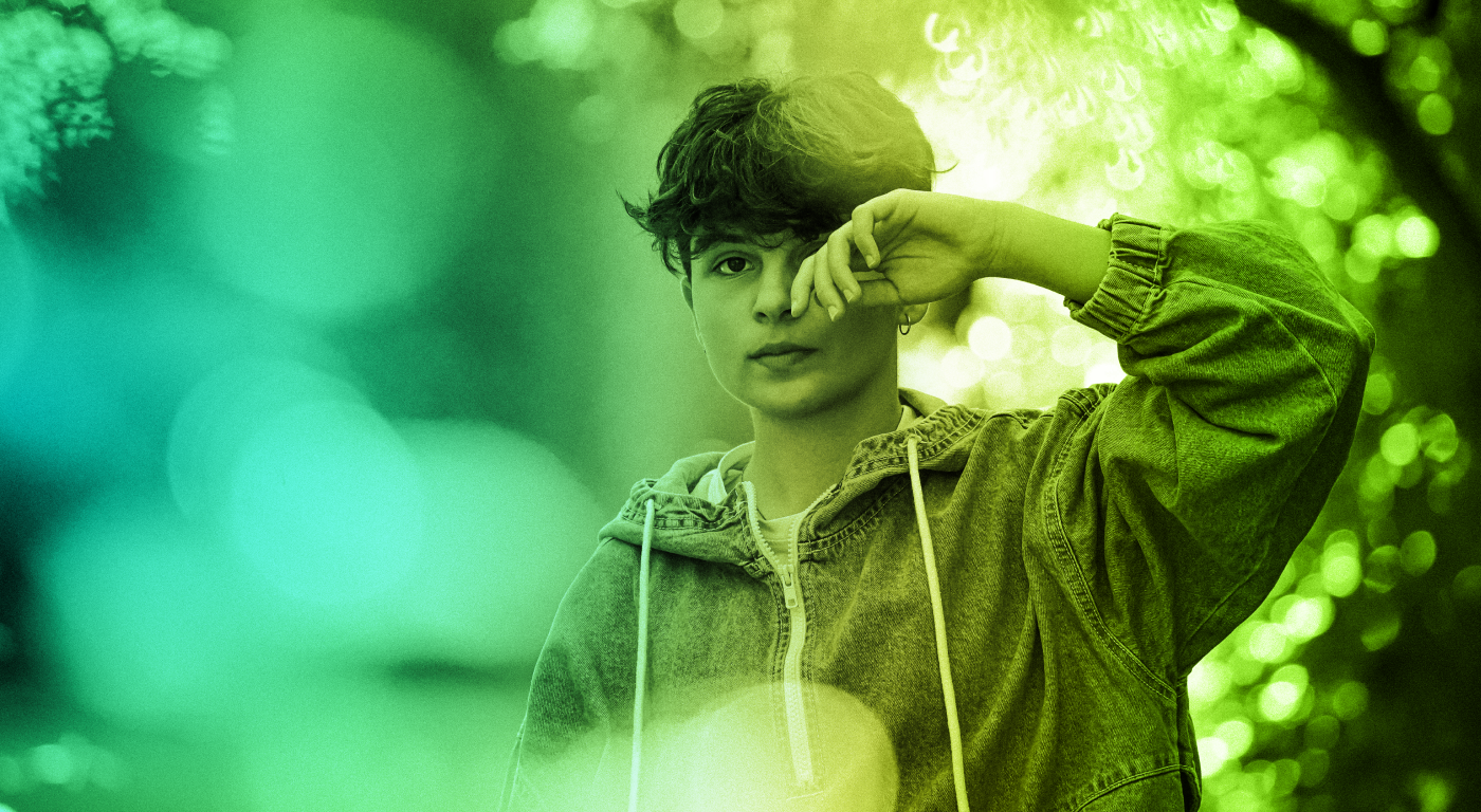 A teal and green gradient-colored photo of young person on a hike, anxiously looking ahead.