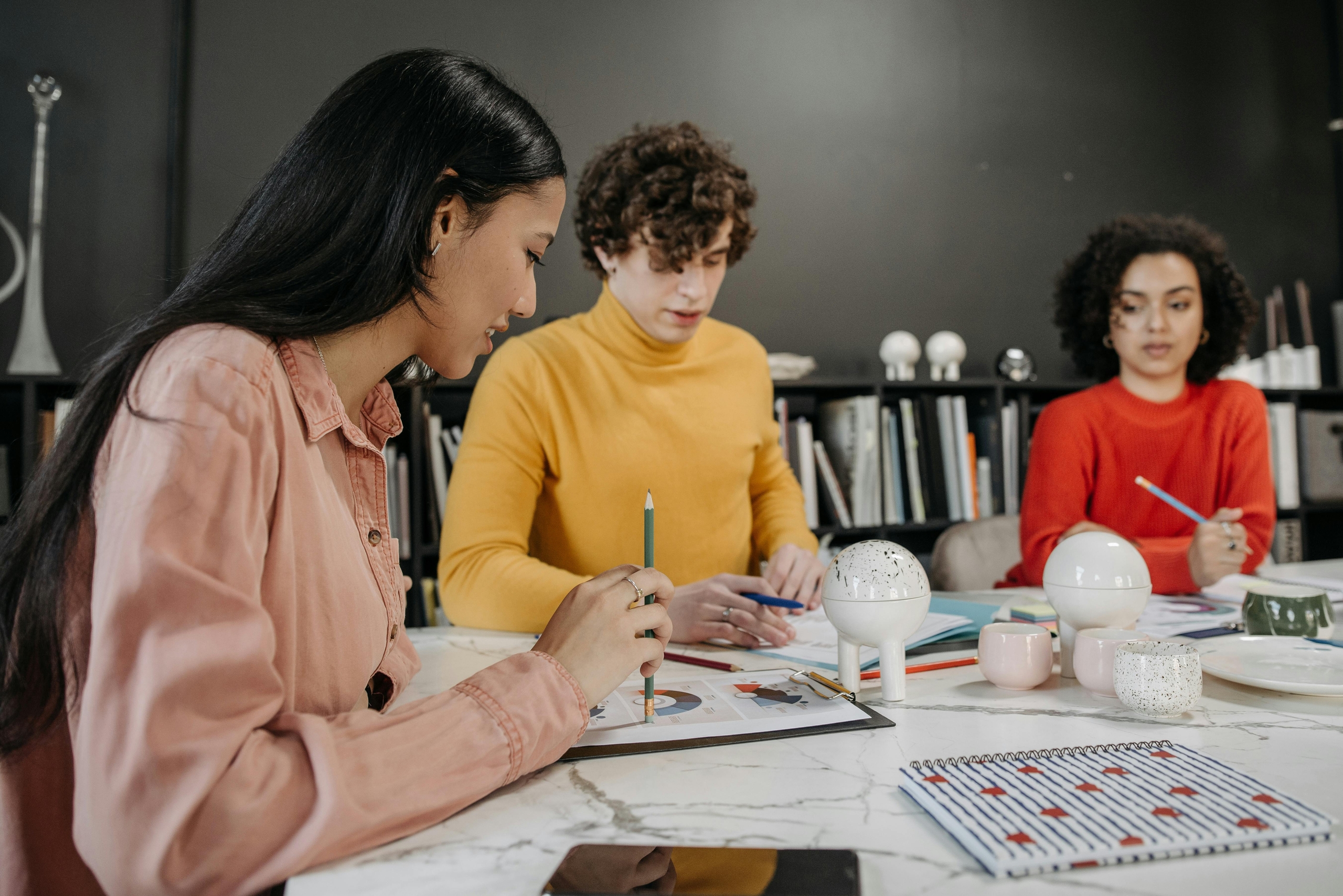 A group of 3 young people collaborating on financial reports