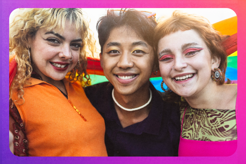 Young people posing under a rainbow flag