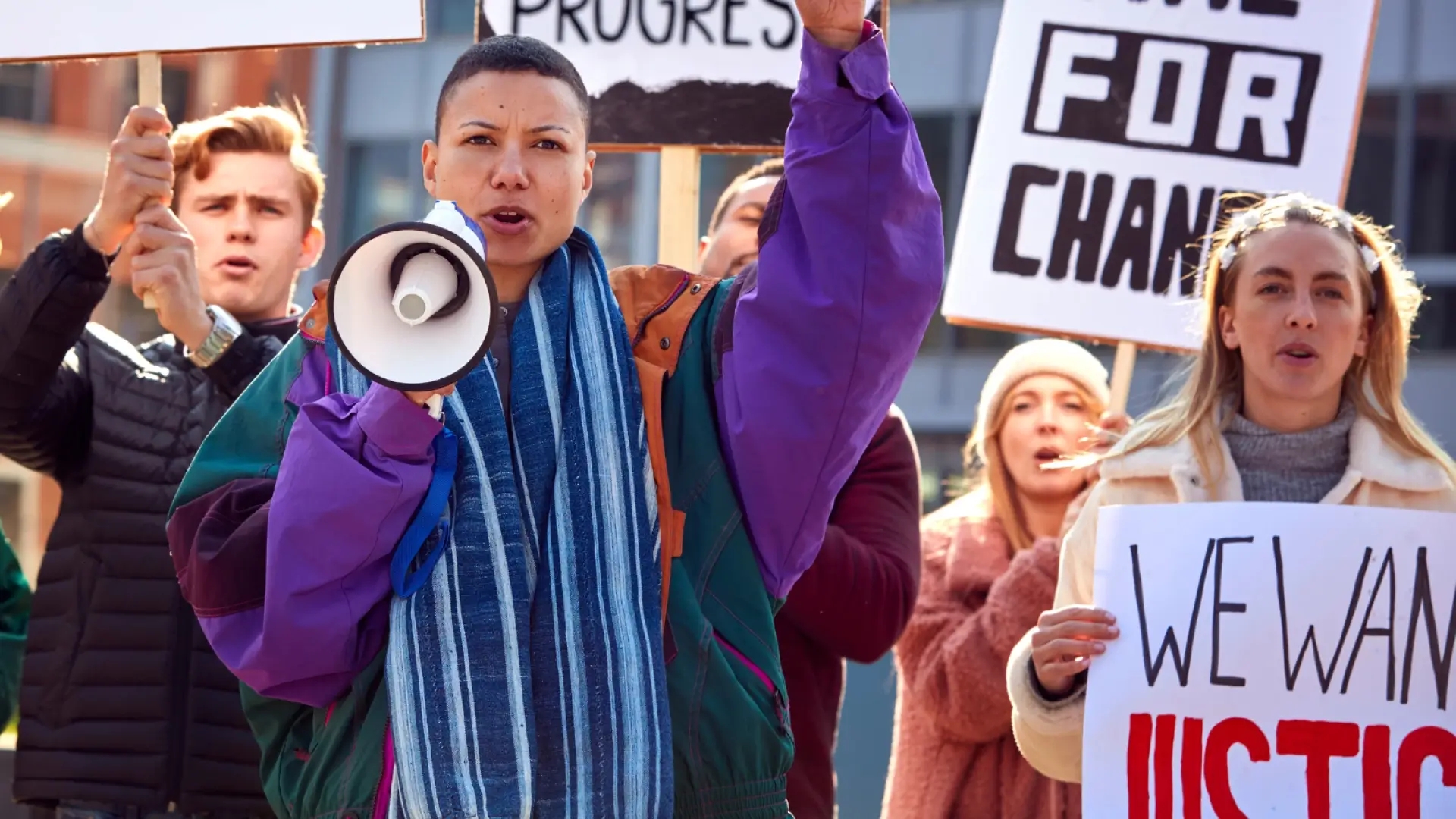 Four young people hold signs reading we want change and we want justice in support of their causes.