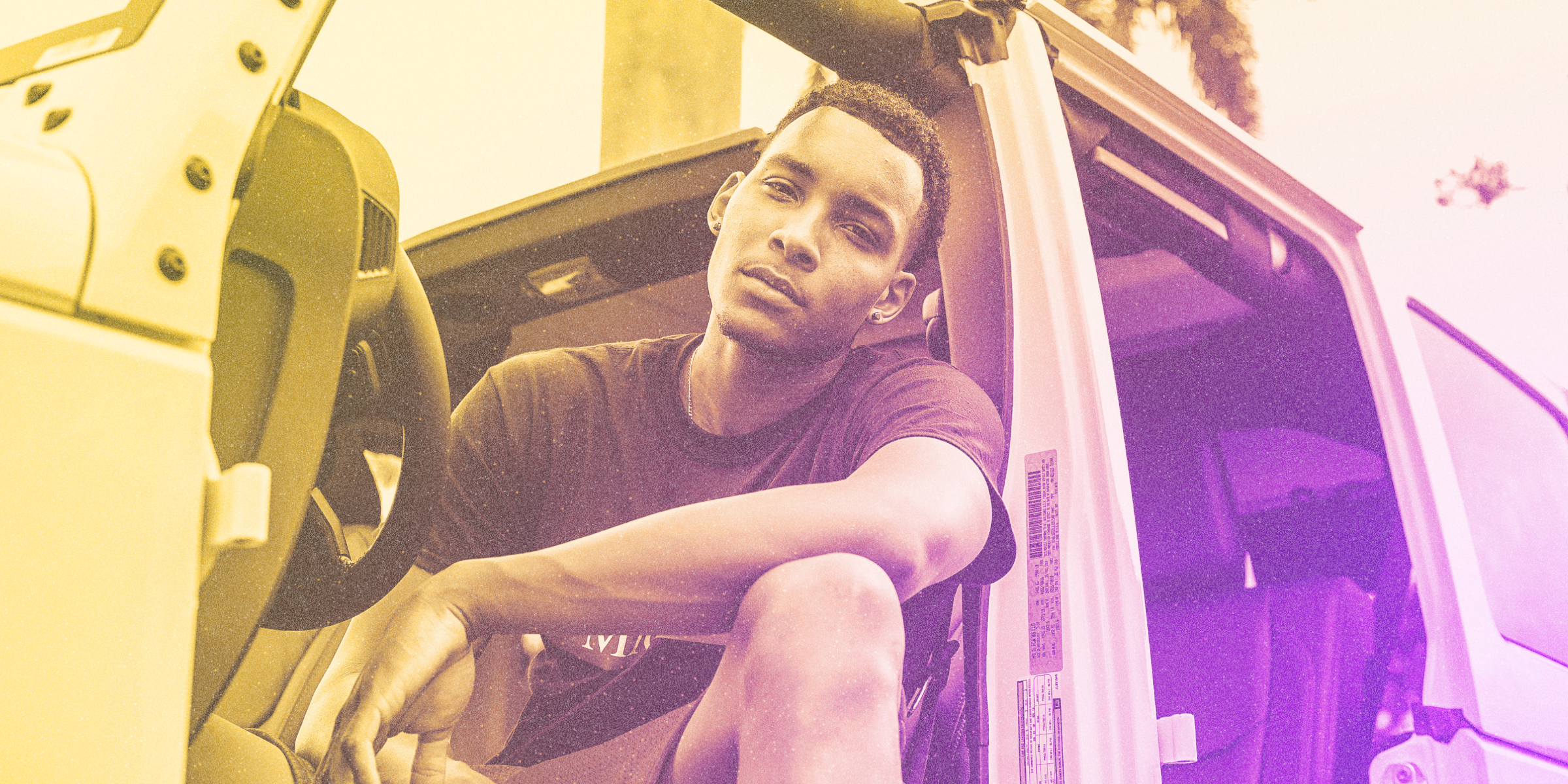 A DoSomething member wearing a t-shirt sitting in a jeep, leaning outward through the door.