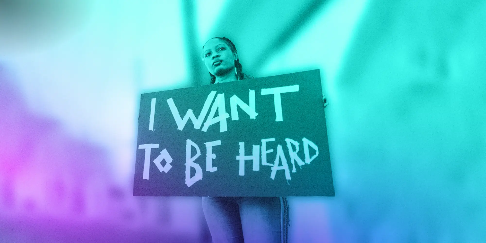 Young person holding up a cardboard sign with "I want to be heard" written on it