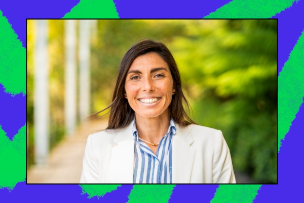 A smiling individual stands outdoors in a well-lit environment, wearing a light blazer over a striped shirt, showcasing a welcoming demeanor. The background features lush greenery, symbolizing growth and community engagement.