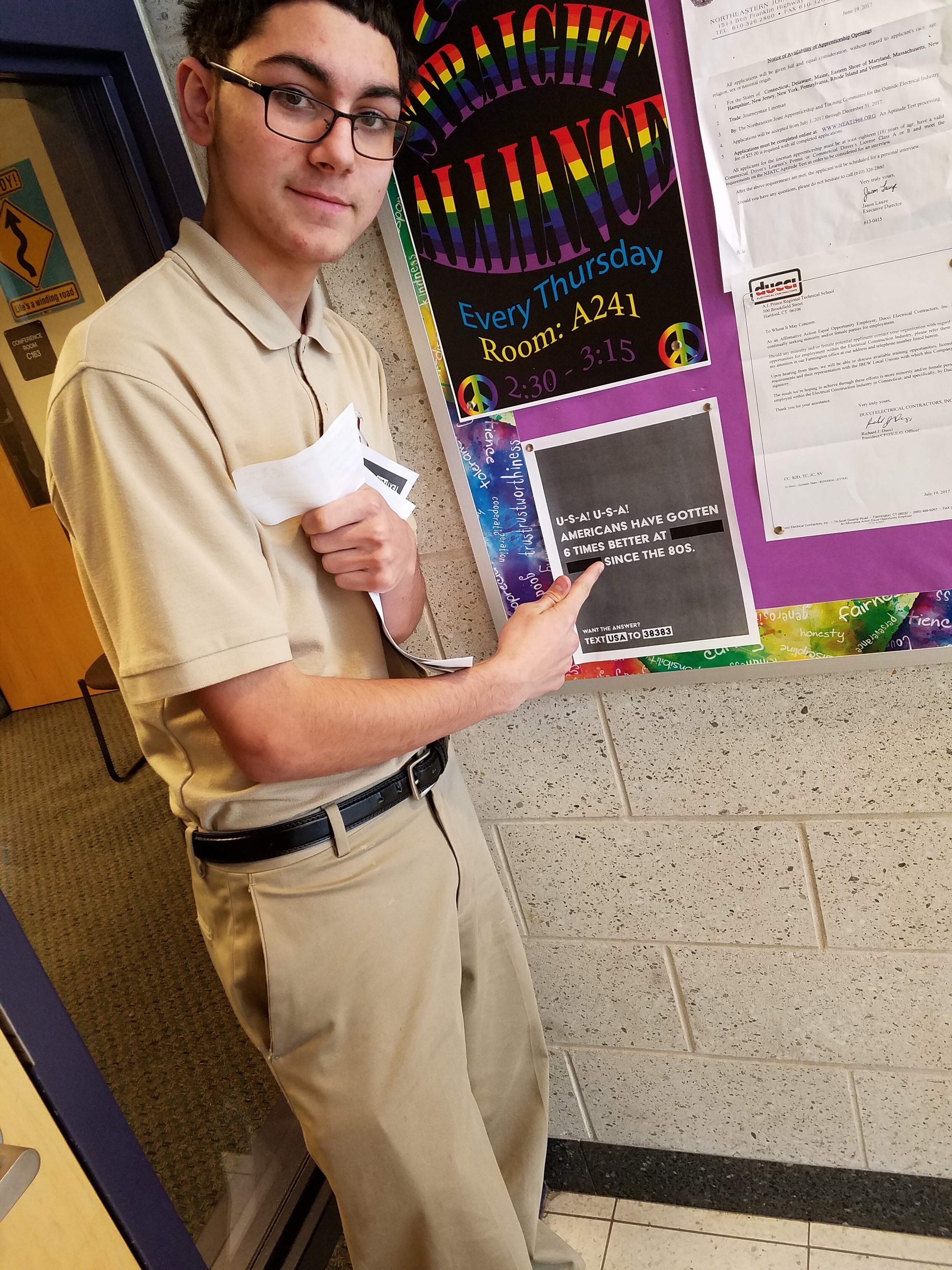 A youth stands next to a bulletin board, pointing at a poster that states, 'Americans have gotten 6 times better at... since the 80s.' The bulletin board features colorful announcements for the Straight Alliance meetings and various community service opportunities.
