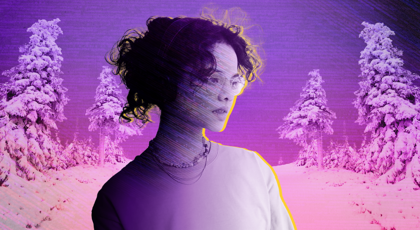 Young person with loose curly hair in an updo, glasses, and long sleeve top against a pink-purple gradient background of snow covered evergreen trees