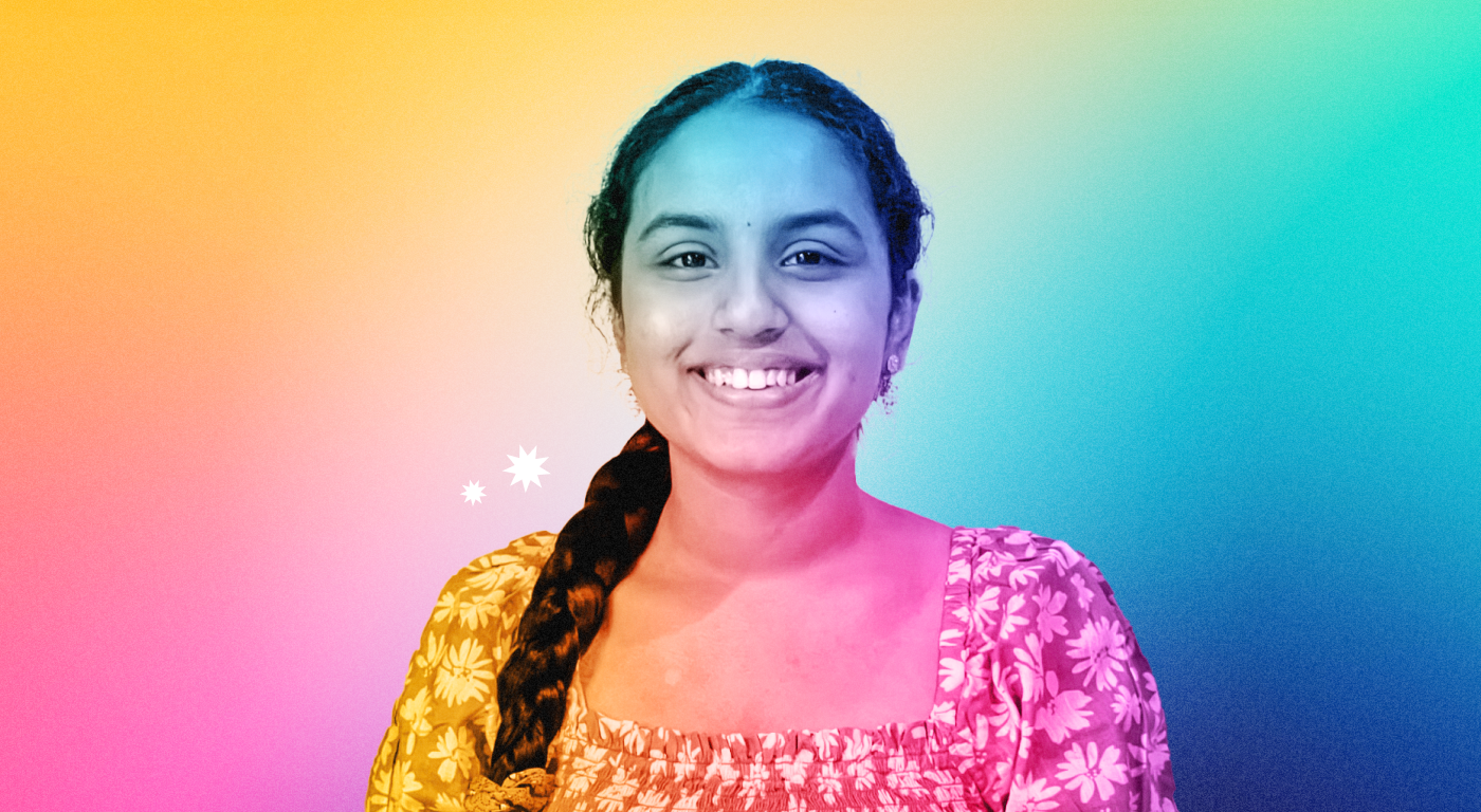 Ananya Pinnamaneni with hair in a center part and long braid, wearing a floral top, looking straigt on and smiling, on an abstract gradient background