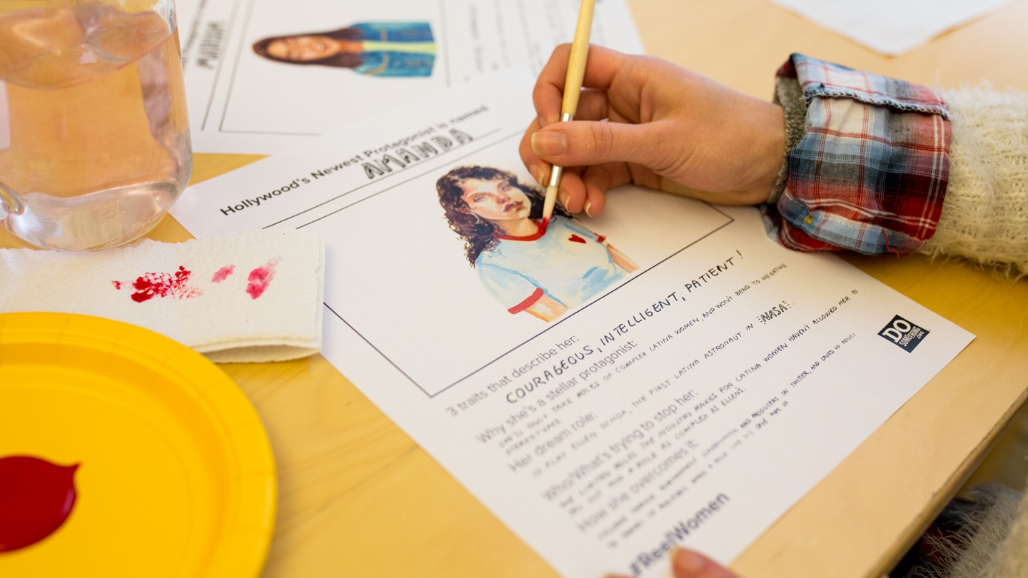 A person drawing a picture of a reelwoman on a paper template