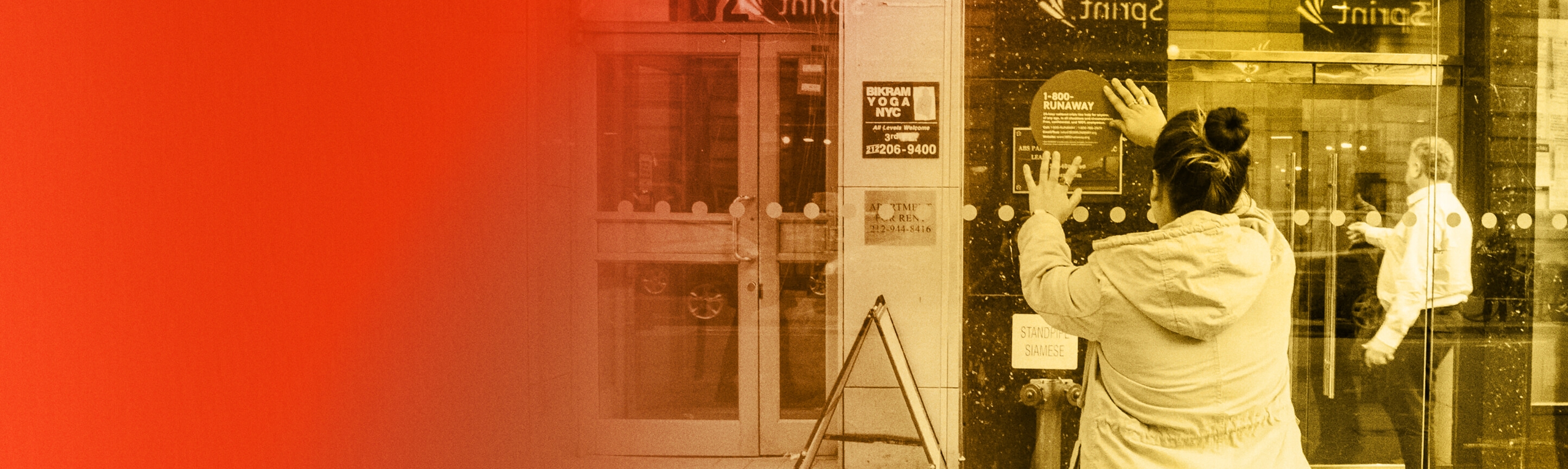 A young person hangs a flyer on a store window