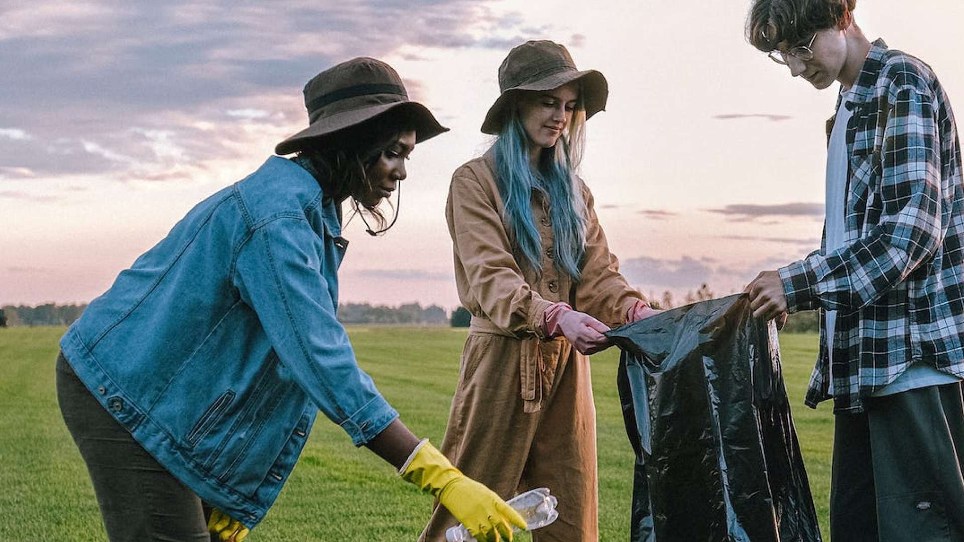 A diverse group of 3 young people cleaning up trash in their community.