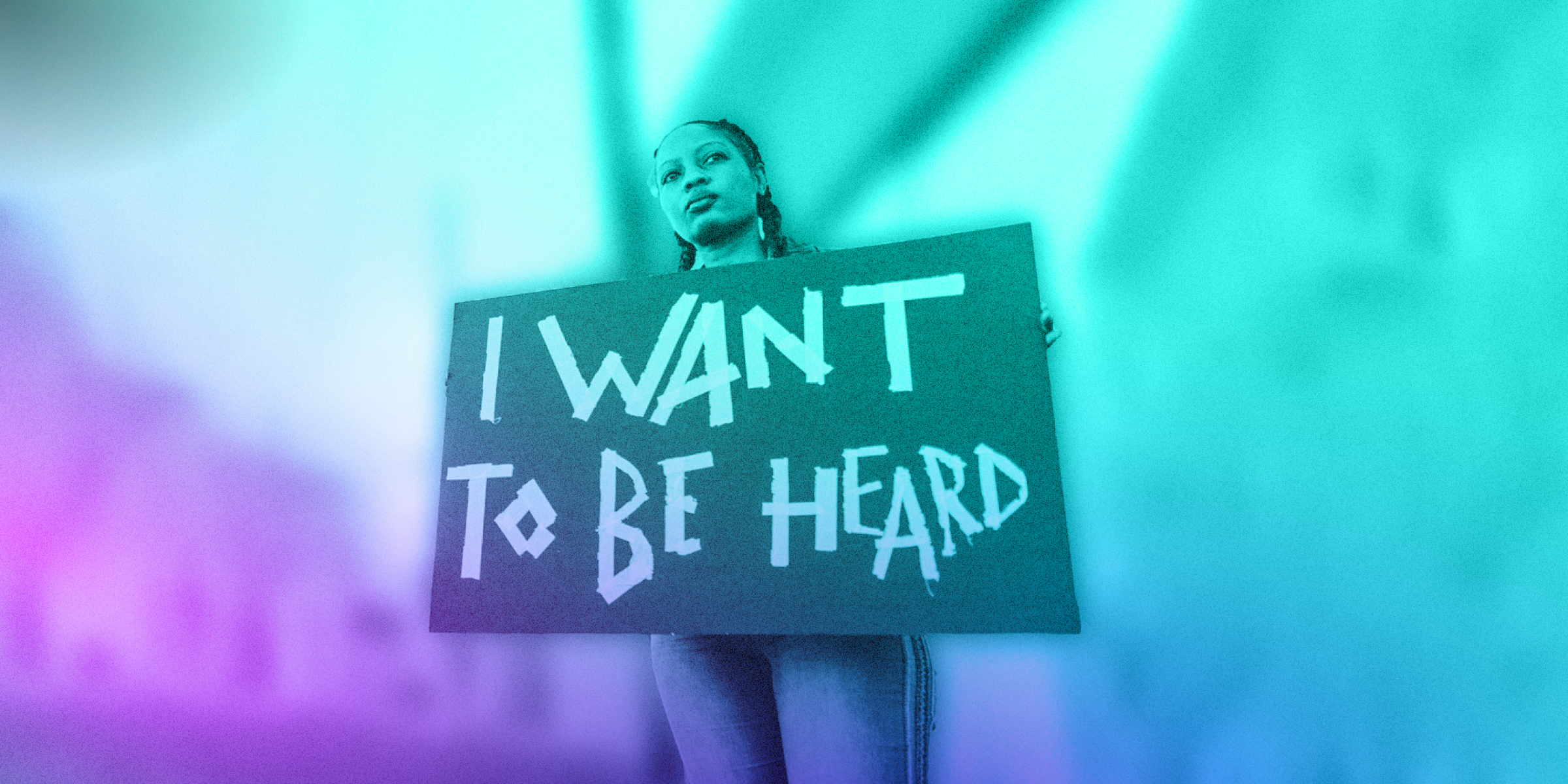 Young person holding up a cardboard sign with "I want to be heard" written on it