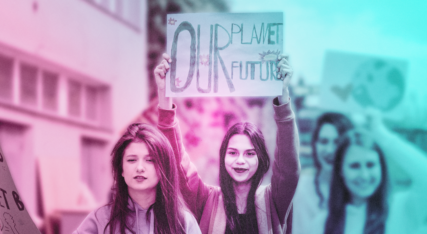 A group of four young people with long straight hair, one is holding up a sign reading "our planet our future"