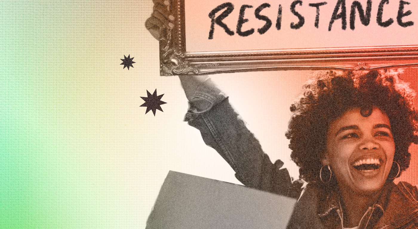 Widely smilingin young person wearing a demin jacket, hoop earings, and with natural hair holding high a fancy carved picture frame saying "resistance" in hand painted lettering