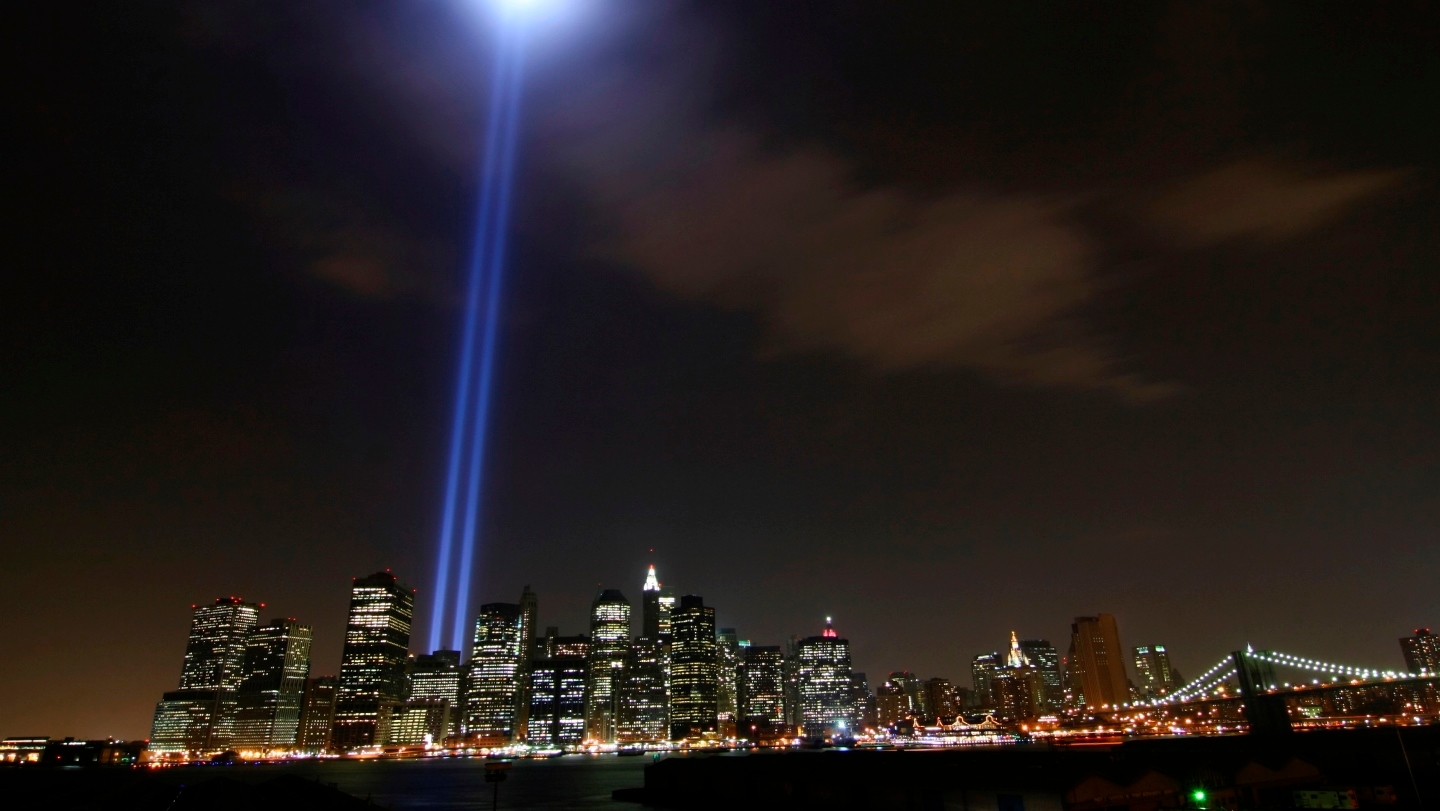 Nighttime view of the NYC skyline with the Tribute in Light twin beams shining upwards brightly from the 911 site.