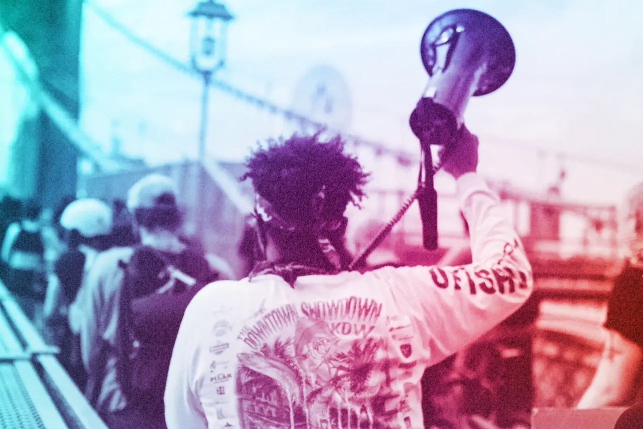 A DoSomething member holds a megaphone while marching across a bridge.