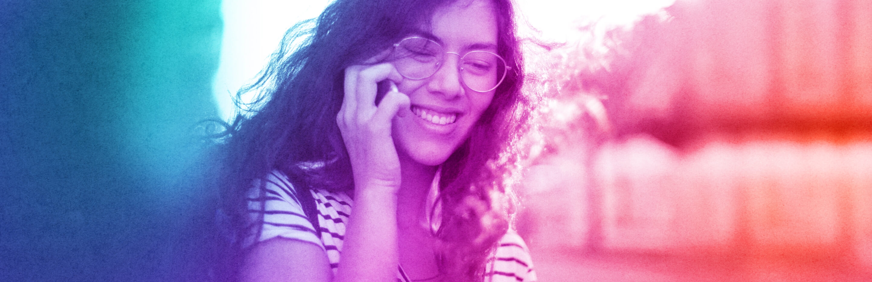 A teal, purple and red gradient-colored graphic image of a young person happily talking on their cellphone.